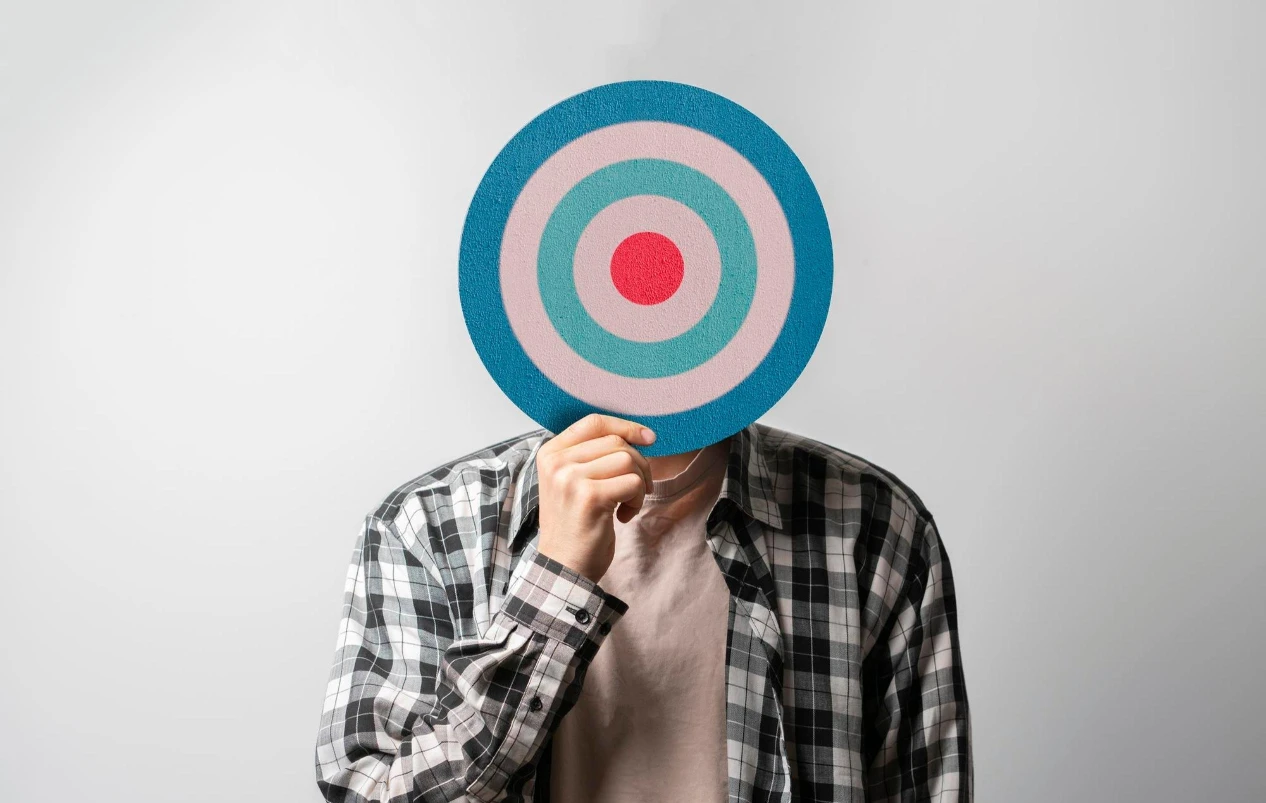 A Person is Holding a Dart Board in front of His Face