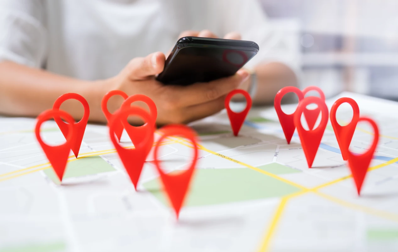 Several Location Icons and a Person Working by his Mobile Phone